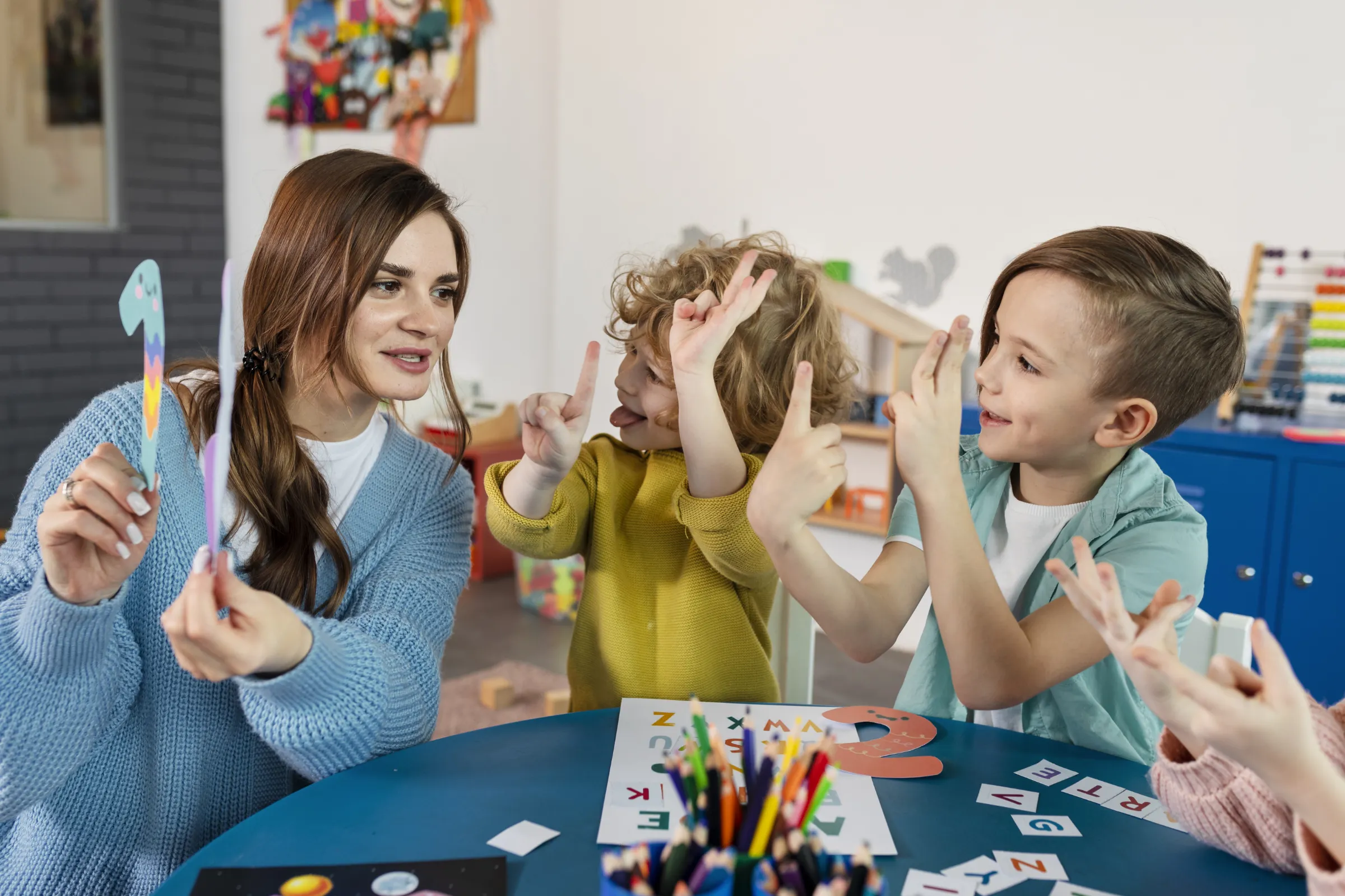 Eine Kindergartengruppe sitzt mit Erzieherin an einem Tisch. Die Kinder üben Zahlen.
