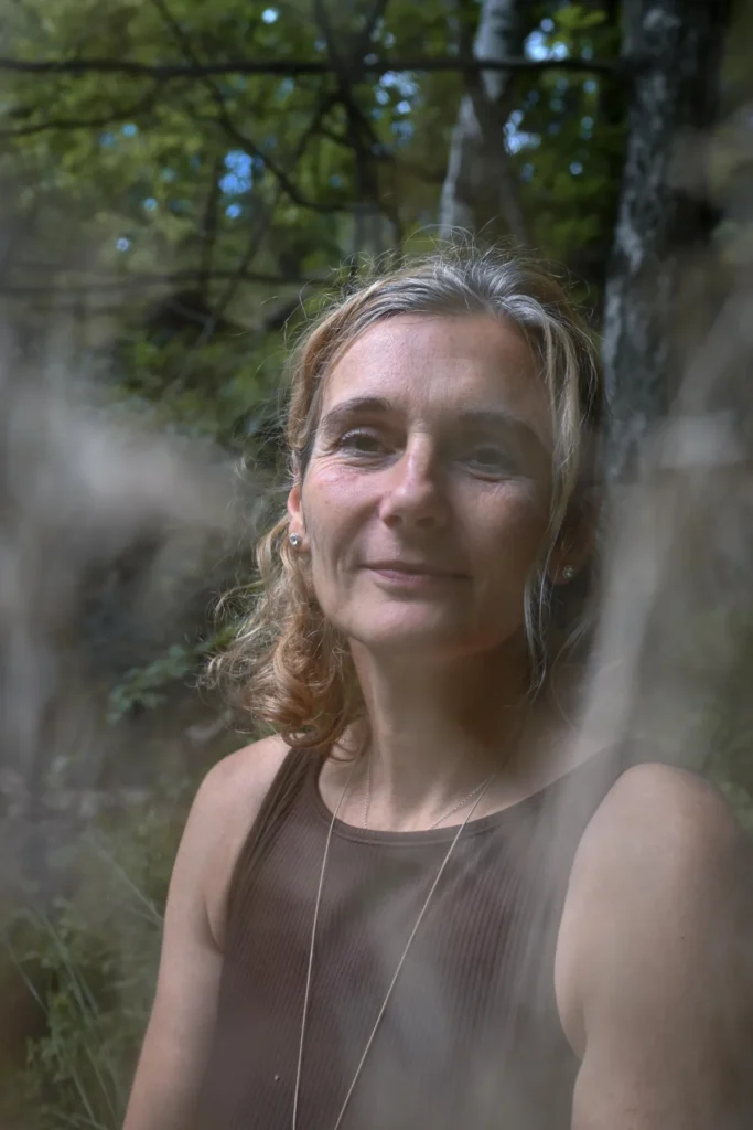 Porträt Martina Schneider-Just. Sie schaut direkt in die Kamera. Im Hintergrund befinden sich Bäume.